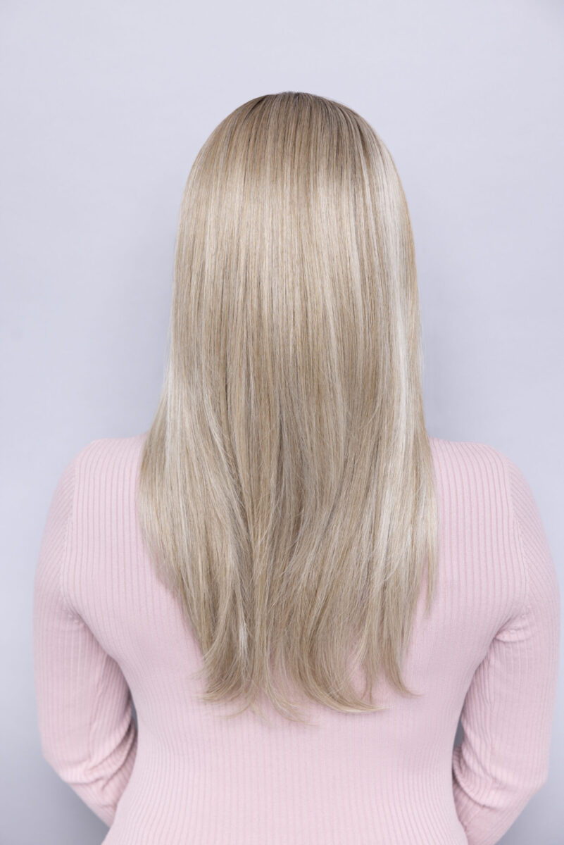 Person with straight, long, blonde hair wearing a light pink ribbed top, shown from the back against a plain background.